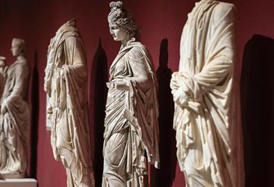 White marble statues against a red wall