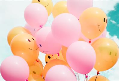 Yellow and pink balloons against a blue sky