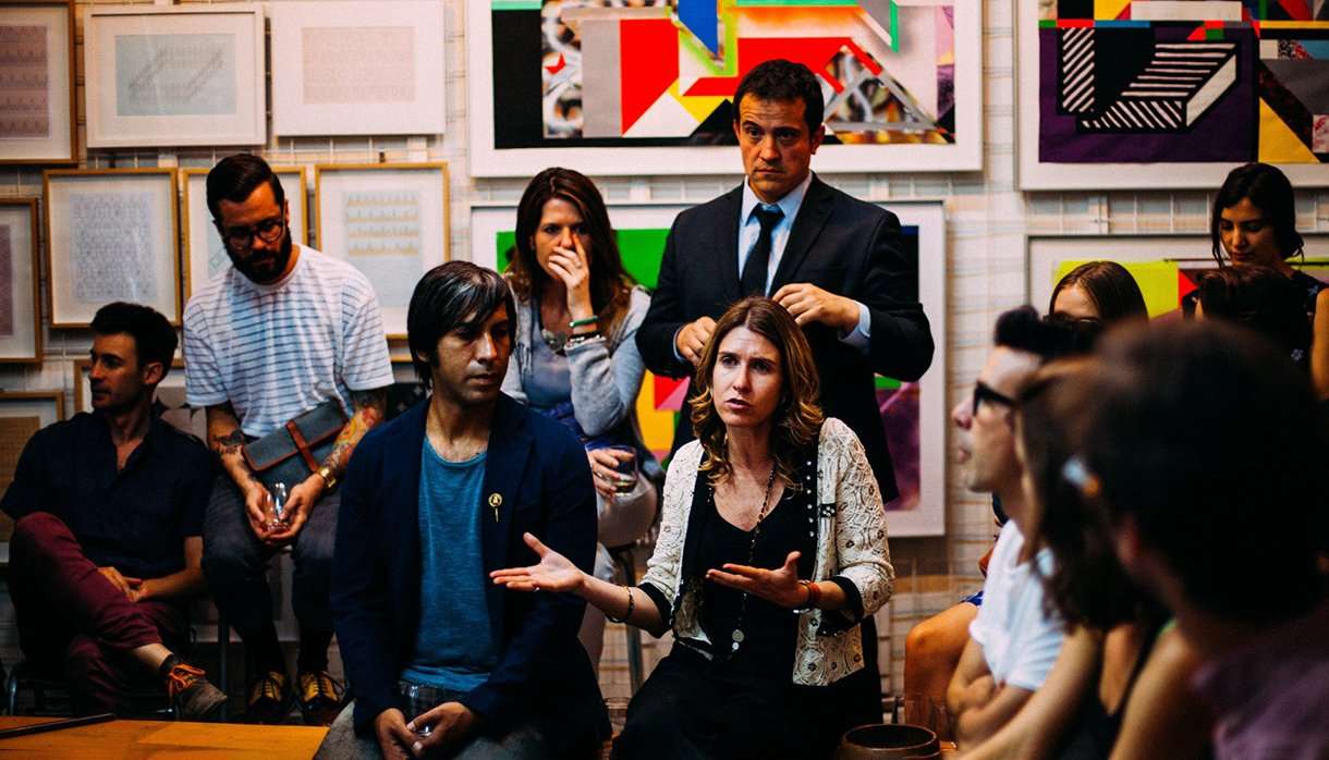 Group of people having a discussion with art on walls behind them