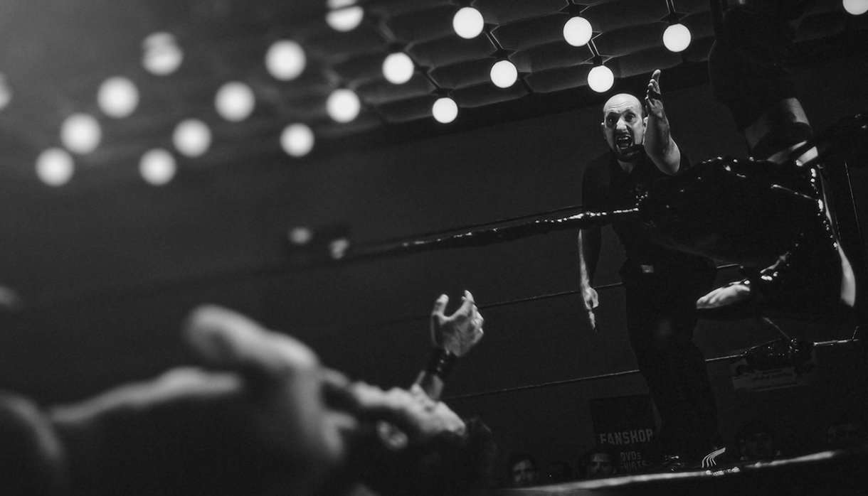 Wrestler down in the ring and referee gesturing with arm