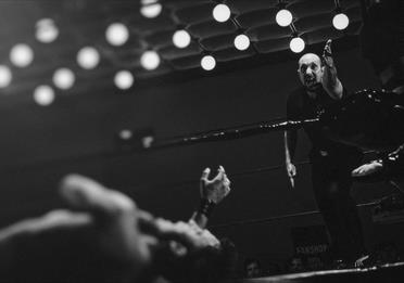 Wrestler down in the ring and referee gesturing with arm