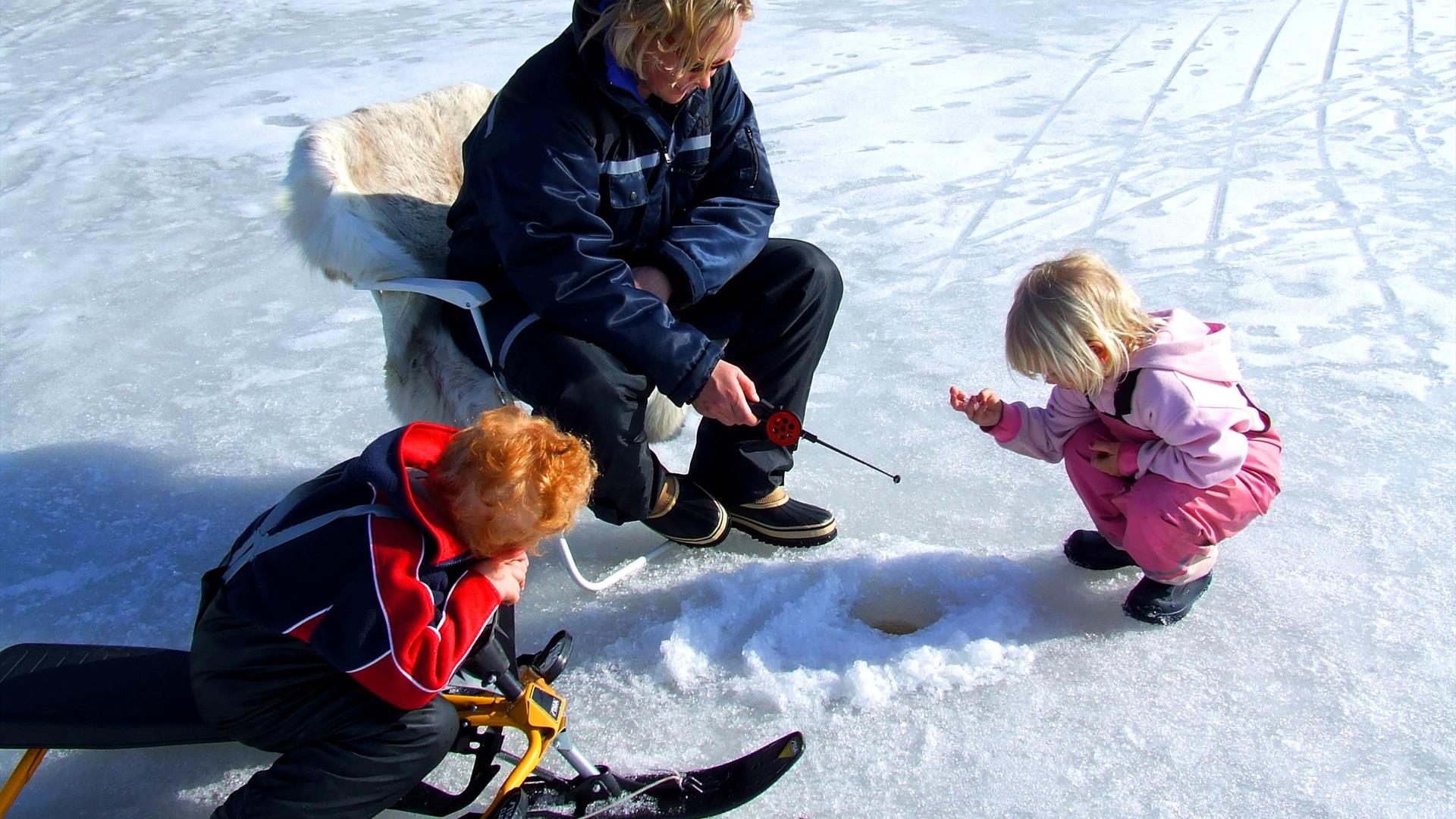Glad familie på isfiske