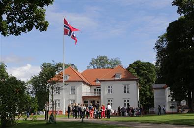 Big white house med norwegian flag and people outside