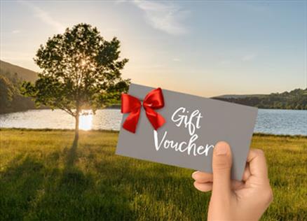 Person holding a gift voucher against a dramatic sunset at Loweswater in the Lake District, Cumbria