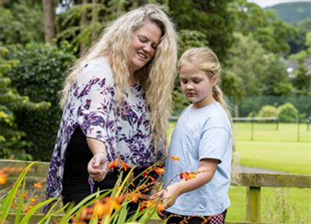 Mother and child look at bright flowers in a park