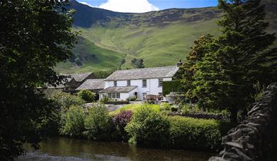 Exterior view from over the river of Grange Bridge Cottage in Borrowdale, Lake District