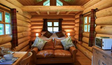 Interior of The Cabin at Grizedale Forest, with a double bed, sofa, small kitchenette, and dining table for two.