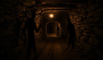 dimly lit mine shaft with multiple shadows against the wall