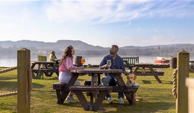 Guests sitting outside with drinks and a dog at The Wateredge Inn in Ambleside, Lake District