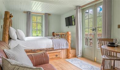 Interior of Juniper Lodge, with double bed, couch, and dining setup at Coniston Shepherd Hut Lodges in Coniston, Lake District