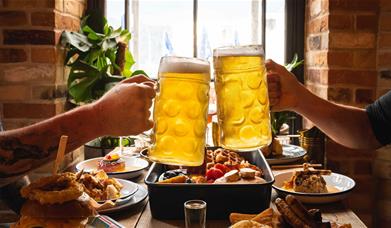 Visitors Toasting Beers over a Table with Food at Lake View Garden Bar in Bowness-on-Windermere, Lake District