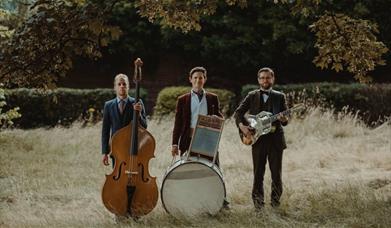 Photo of "Leeds City Stompers" standing in a field with their respective instruments