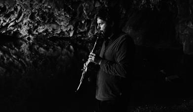 A person playing a clarinet in a cave