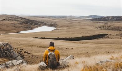 A person sitting on a hill overlooking a lake in Cumbria