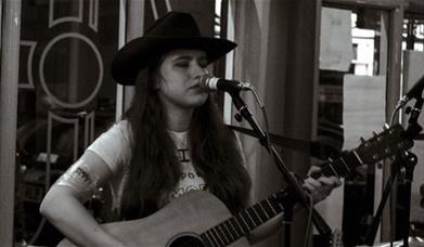 Susannah Clegg singing live while playing the guitar