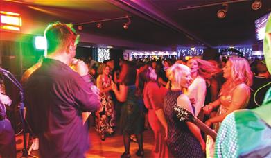 A singer and guitarist performing to a crowd of dancing people