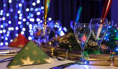 Picture of a Christmas party dinning table with crackers and fairy lights