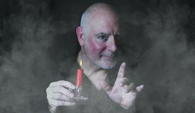 Photo of Scrooge holding a candle surrounded by mist