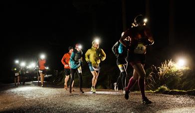 A group of people racing with head touchers on running at night