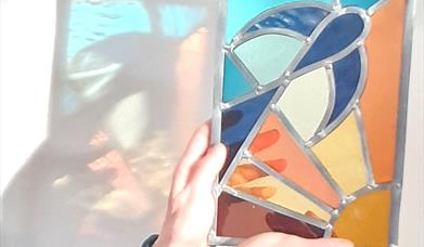 A person holding up a stained glass artwork