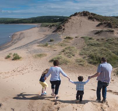 Family walking hand in hand on a sand dune on a sunny day