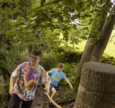 two kids walking along a woodland trail