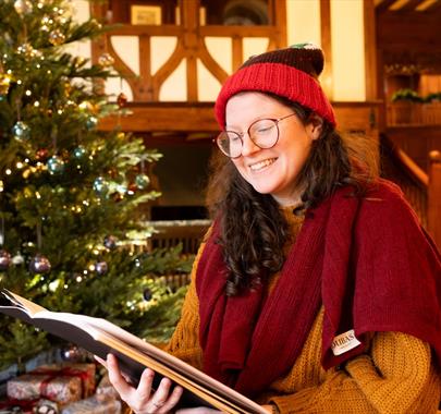 Women smiling while reading a book by a Christmas tree