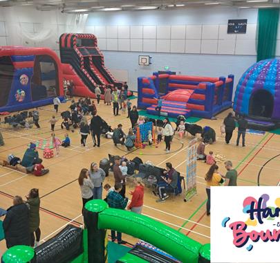 Indoor family fun event with large inflatable obstacle courses, bouncy castles, slides, and activity areas. Children and parents are playing, while ot