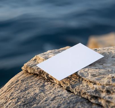 a piece of a paper sat at the end of a rock overhanging a body of water