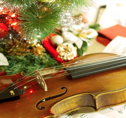 Violin placed face up next to a Christmas tree