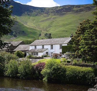 Exterior view from over the river of Grange Bridge Cottage in Borrowdale, Lake District