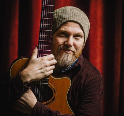 Photo of EP Stephens hugging his guitar