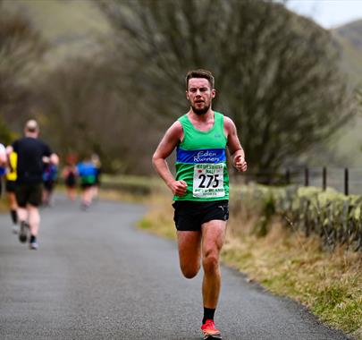 A man running along a rural road with a backdrop of mountains