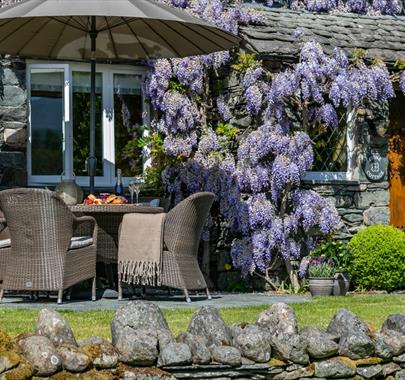 Exterior of Stone Cottage in Patterdale, Lake District with Wisteria and outdoor patio seating