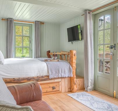 Interior of Juniper Lodge, with double bed, couch, and dining setup at Coniston Shepherd Hut Lodges in Coniston, Lake District