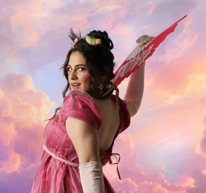 A still from the play Clementine featuring Clementine fanning herself with a backdrop of clouds
