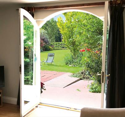 Double doors leading to the garden and outdoor seating at The Cottage at Linden Farm House in Langwathby, Cumbria
