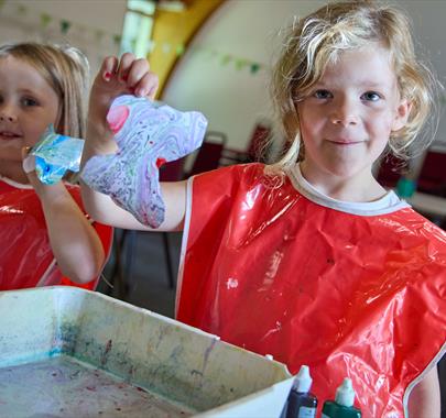 two smiling girls holding some art they have just made