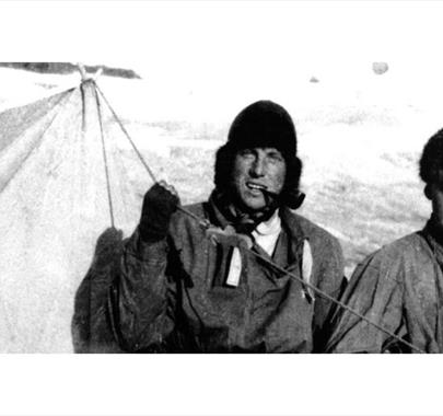 Black and white photo of Sandy Irvine and another mountaineer at a mountain campsite in the snow