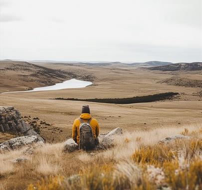 A person sitting on a hill overlooking a lake in Cumbria