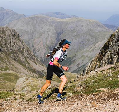 Female fell runner running up a mountain in the lake district Cumbria