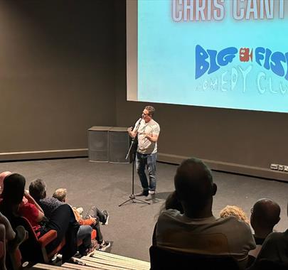 Big Fish Comedy Club live performance involving a crowd watching a male comedian on stage