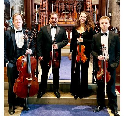 The Northern String Quartet stood in a church with their respective instruments