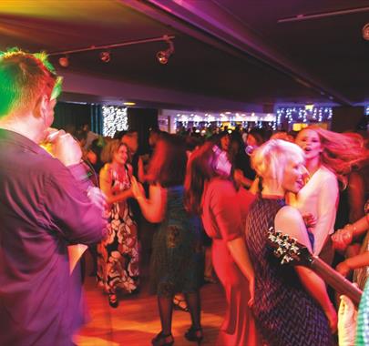 A singer and guitarist performing to a crowd of dancing people