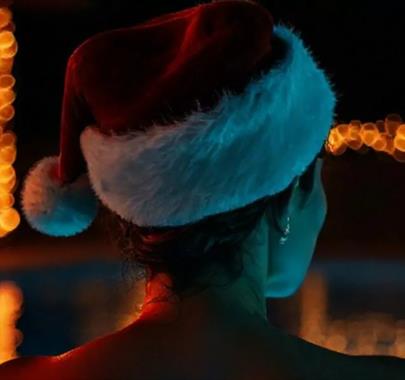 Women wearing a santa hat looking out over a lake at night