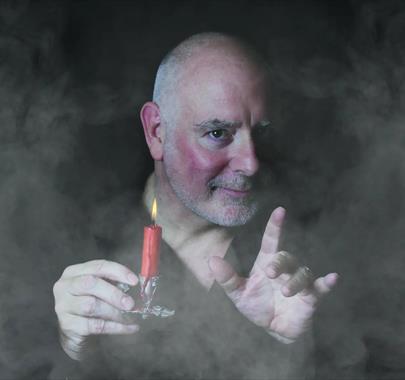 Photo of Scrooge holding a candle surrounded by mist