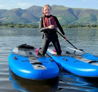 Child with stand-up paddleboards from Newlands Adventure Centre in the Lake District, Cumbria