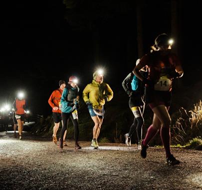 A group of people racing with head touchers on running at night