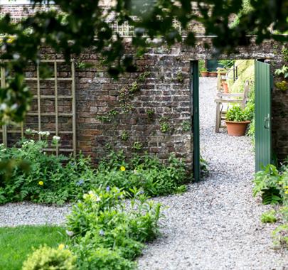 Cumbrian garden with a stone wall and a wooden door leading into a second, hidden garden.