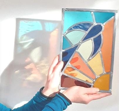 A person holding up a stained glass artwork